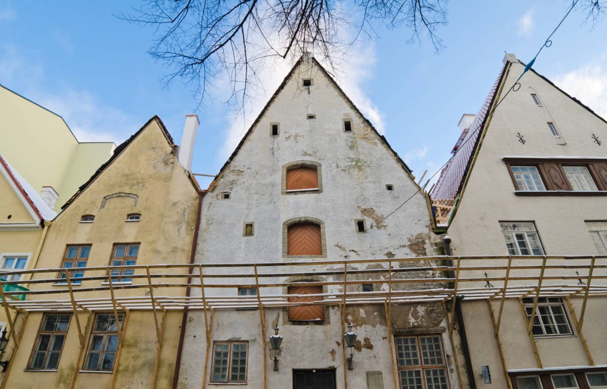 The exterior of three old buildings awaiting a restoration project. A large connecting scaffold is on the buildings.