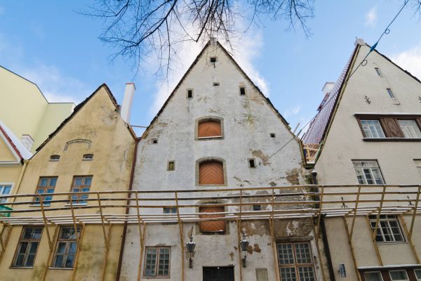 The exterior of three old buildings awaiting a restoration project. A large connecting scaffold is on the buildings.