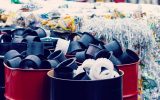 A large collection of paper, plastic, and other forms of waste is stacked, bound, and kept in red barrels.