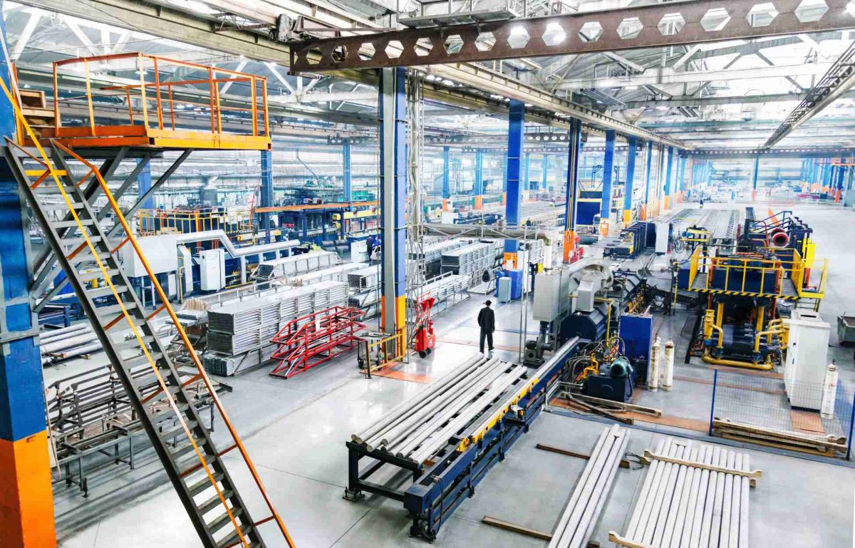 The interior of a clean and well-lit manufacturing plant. The factory features production lines and other heavy equipment.