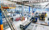 The interior of a clean and well-lit manufacturing plant. The factory features production lines and other heavy equipment.