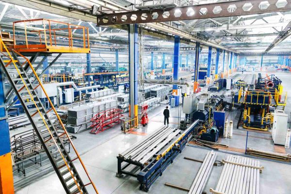 The interior of a clean and well-lit manufacturing plant. The factory features production lines and other heavy equipment.