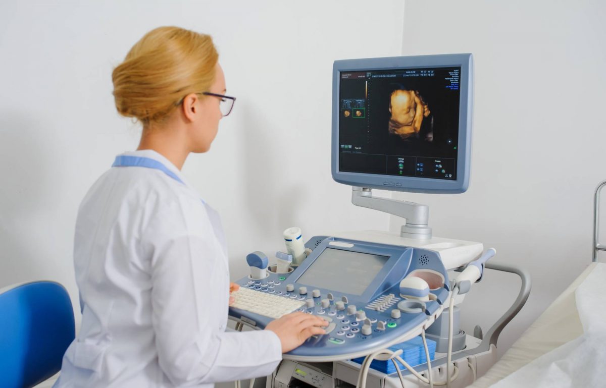 A medical professional using a 3D/4D ultrasound machine. She is currently examining an image on the screen.