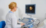 A medical professional using a 3D/4D ultrasound machine. She is currently examining an image on the screen.