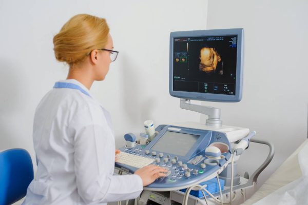 A medical professional using a 3D/4D ultrasound machine. She is currently examining an image on the screen.