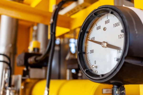 A close-up of an industrial pressure gauge displaying a reading of nearly 400 psi. The surrounding pipes are yellow.