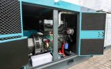 An industrial diesel generator. The front panel of the generator is open and you can see the various components inside.