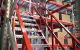 Red and silver steel stairs lead to a red and silver platform filled with stacks of cardboard boxes.