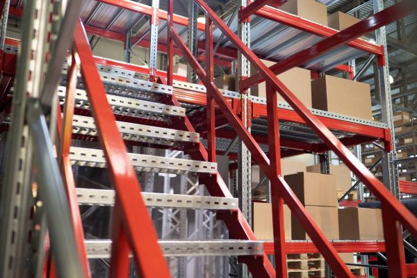 Red and silver steel stairs lead to a red and silver platform filled with stacks of cardboard boxes.