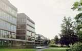 A large commercial building with an all-glass window exterior. The grass is freshly cut and the trees are in full bloom.