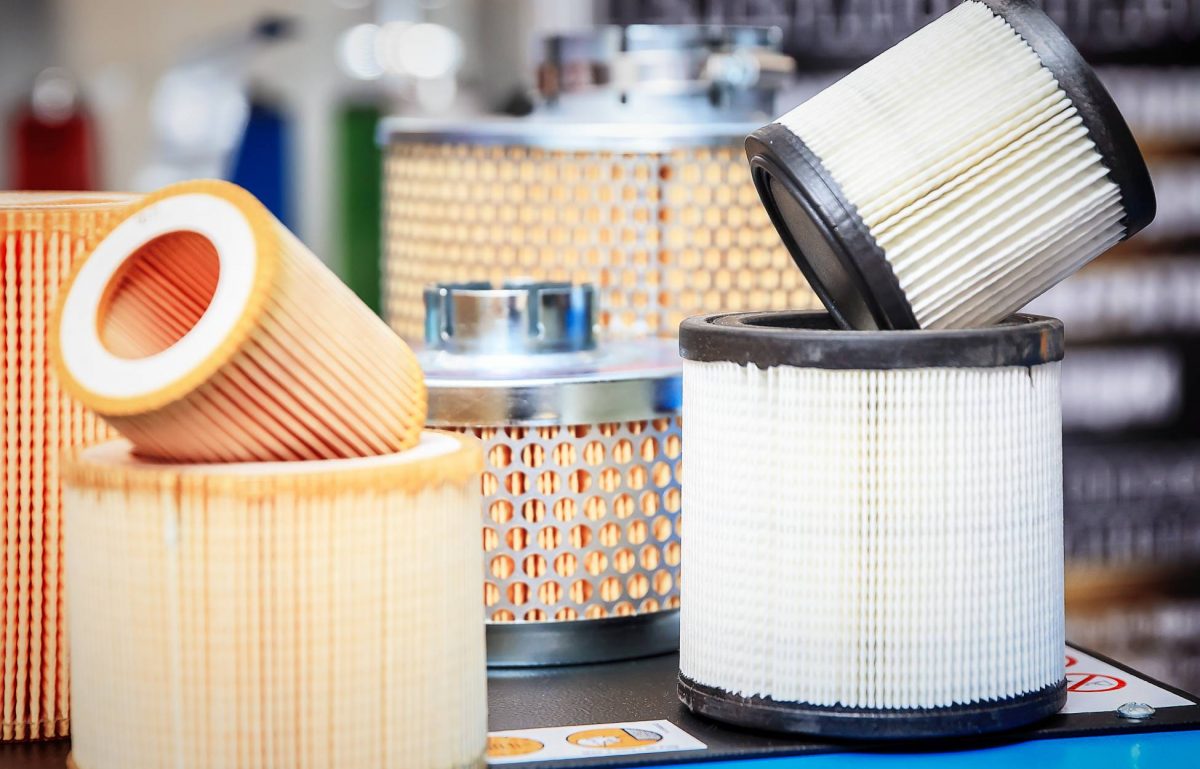 Various hydraulic system filters rest on a table. Each filter has a different size, color, and appearance.