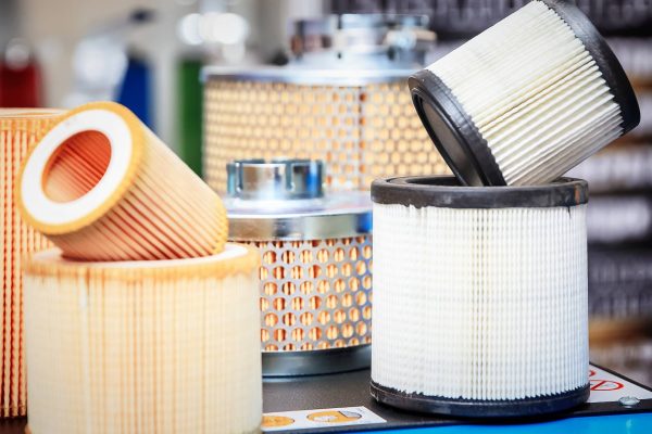 Various hydraulic system filters rest on a table. Each filter has a different size, color, and appearance.