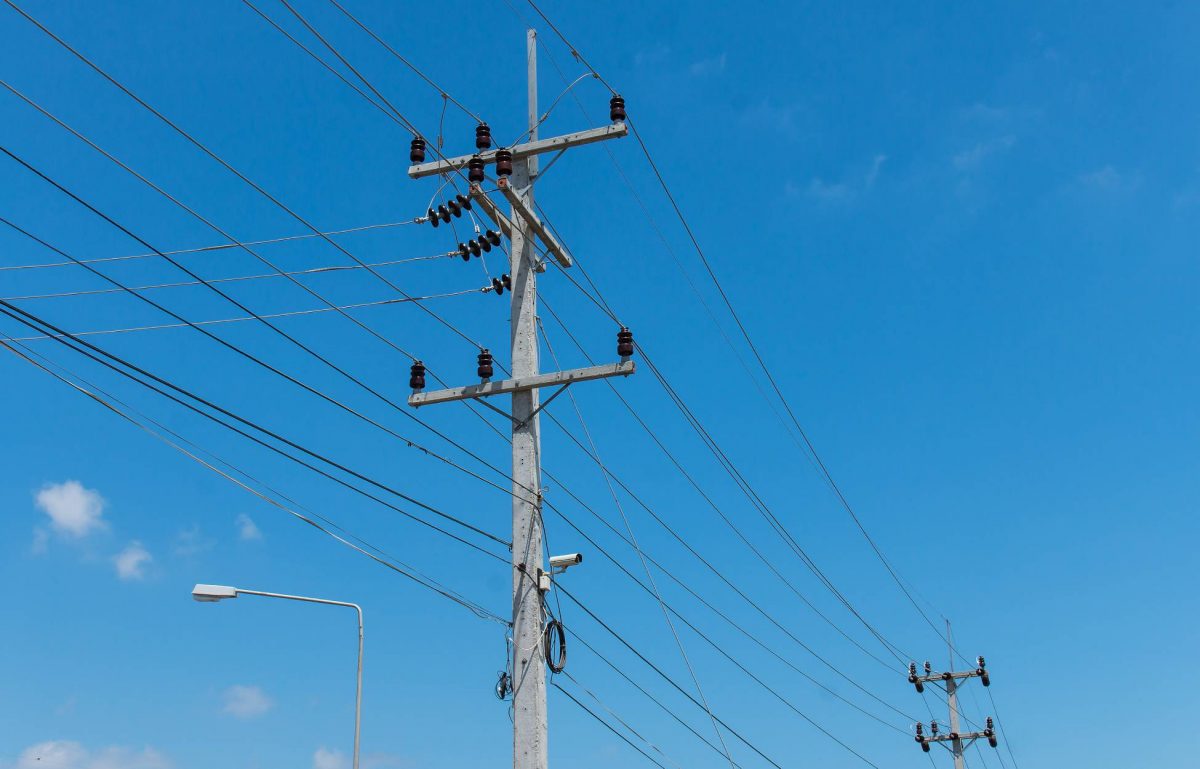 Two electricity posts are connected by running black cables. The background is a blue sky with small clouds on the left side.