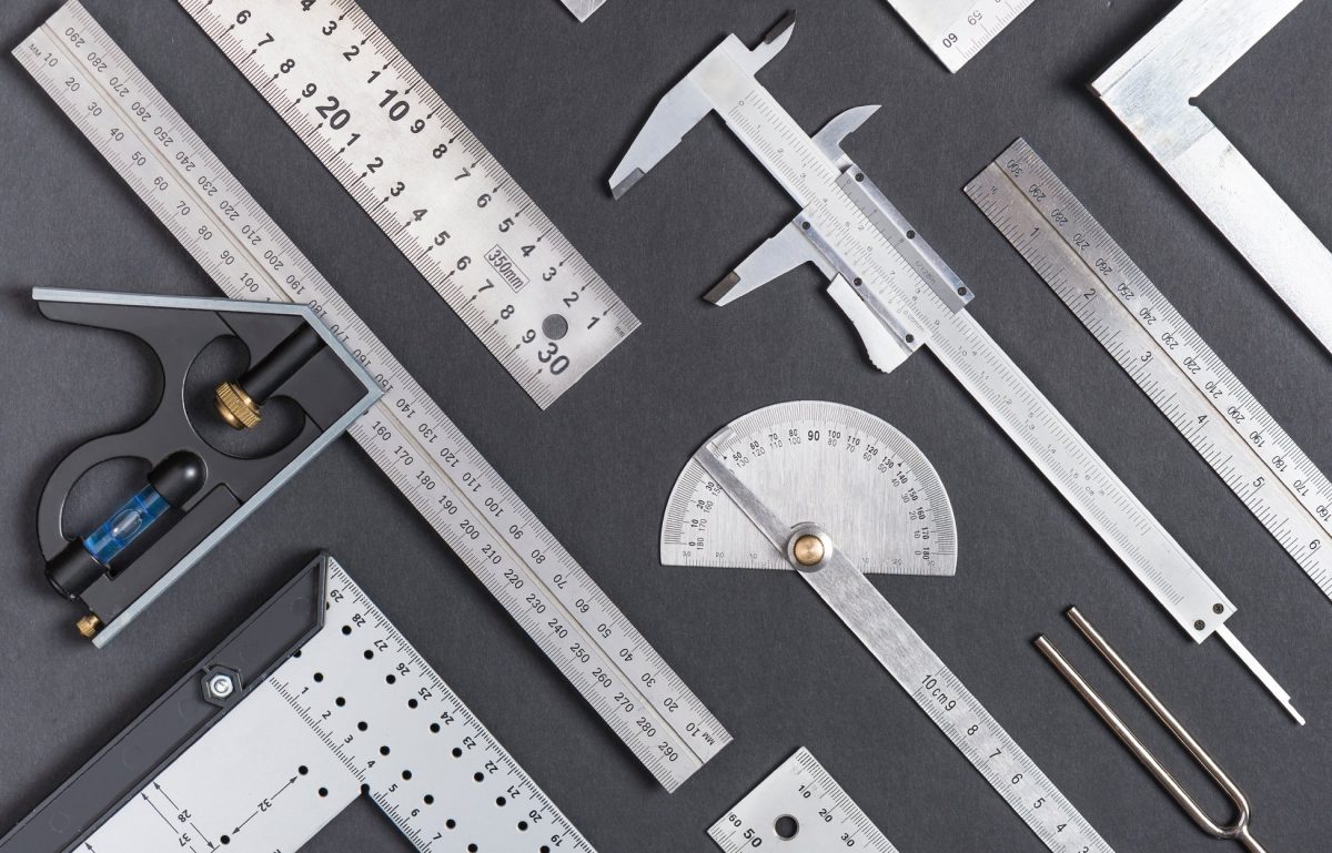 Aerial view of multiple metal measuring instruments laid next to each other on top of a flat gray surface.