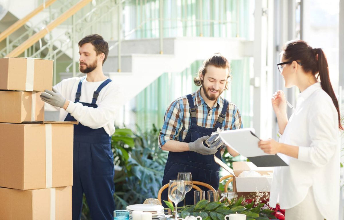 An event planner using her checklist to examine the delivery of decorations while the staff unpack the boxes.