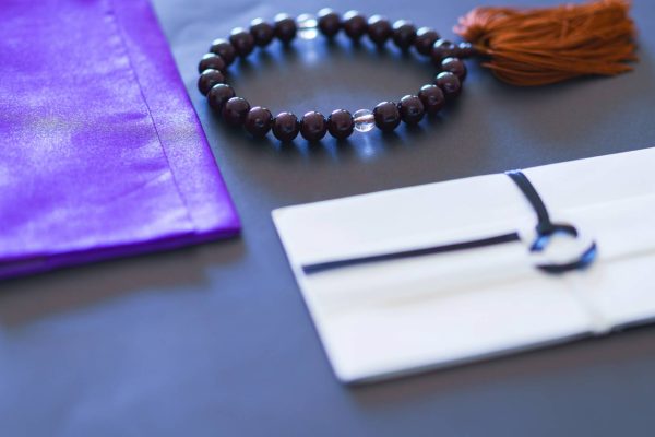 A small collection of First Communion jewelry as a gift. There's a purple bracelet bag and a beaded bracelet next to it.